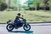 Profile angle of a person riding a green motorcycle on a street.