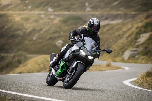 Front angle of a person riding a motorcycle on a winding road. opens in a new window