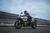 Side angle of a person riding a motorcycle on a road.