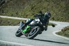 Front angle of a person riding a motorcycle around a bend in a road.