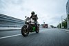 Three-quarter front angle of a person riding a motorcycle on a road.