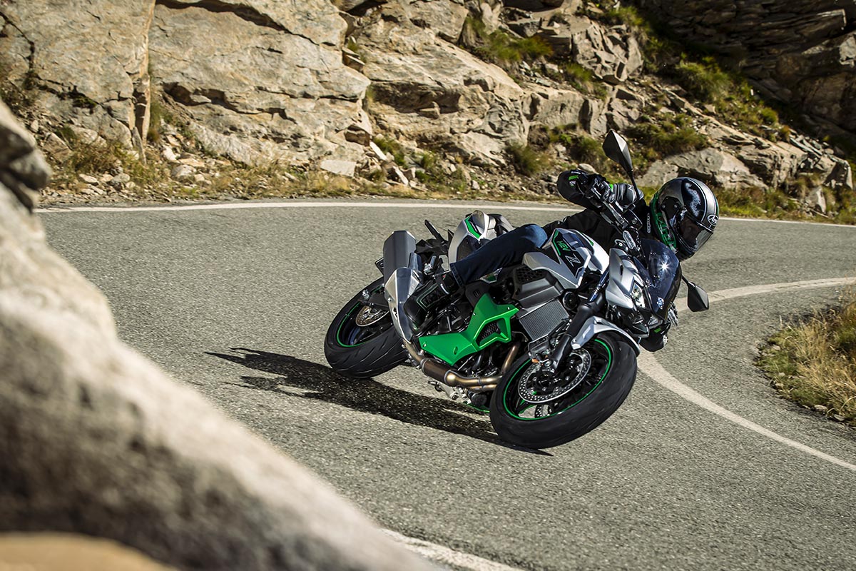 Three-quarter front angle of a person riding a motorcycle around a bend in a road.