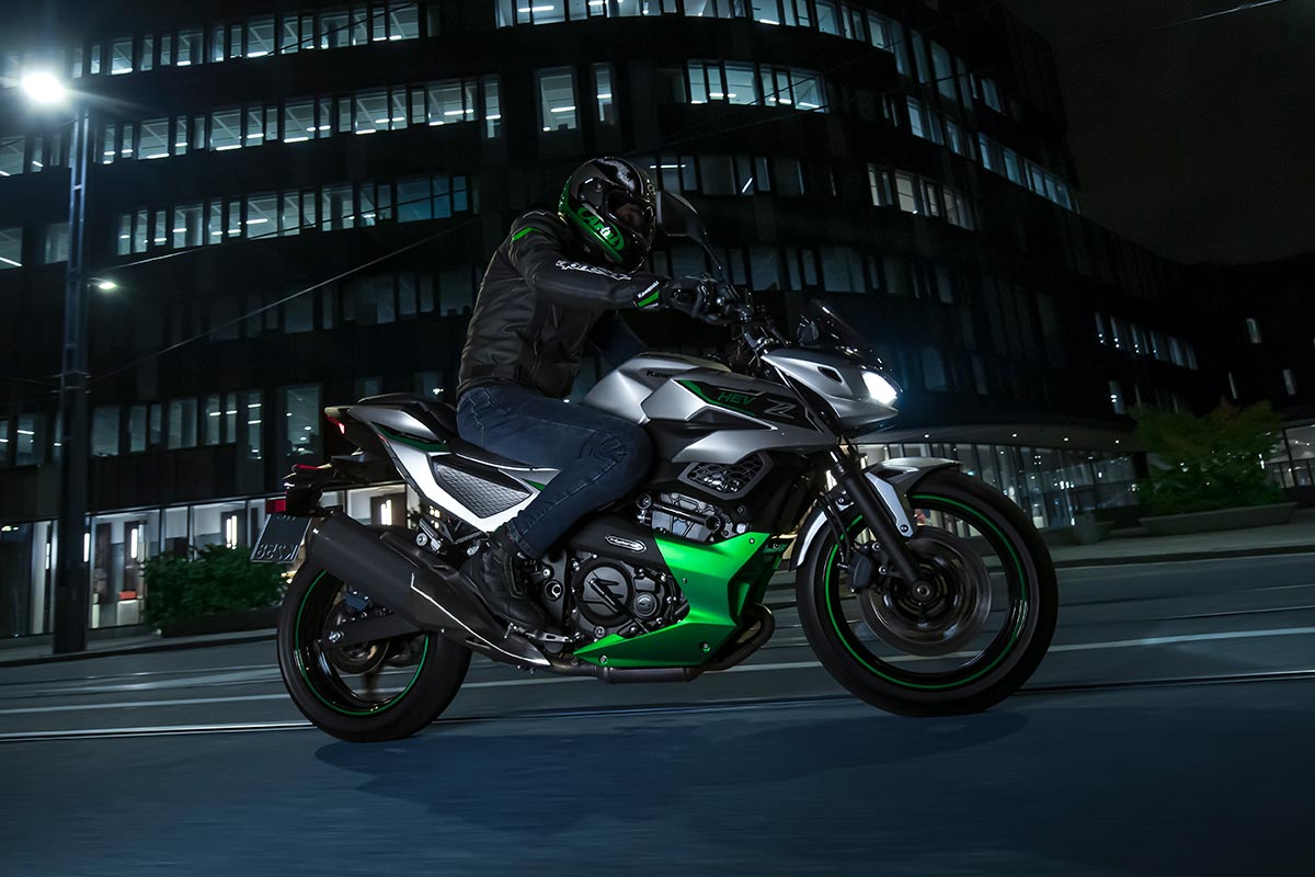 Side angle of a person riding a motorcycle in a city at night.