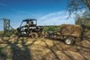 Side angle of a person driving a side x side towing hay.