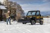 Three-quarter front angle of a side x side parked in the snow.