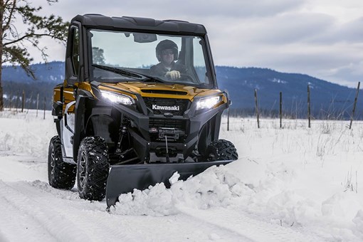 Front angle of a person driving a side x side plowing snow. opens in a new window