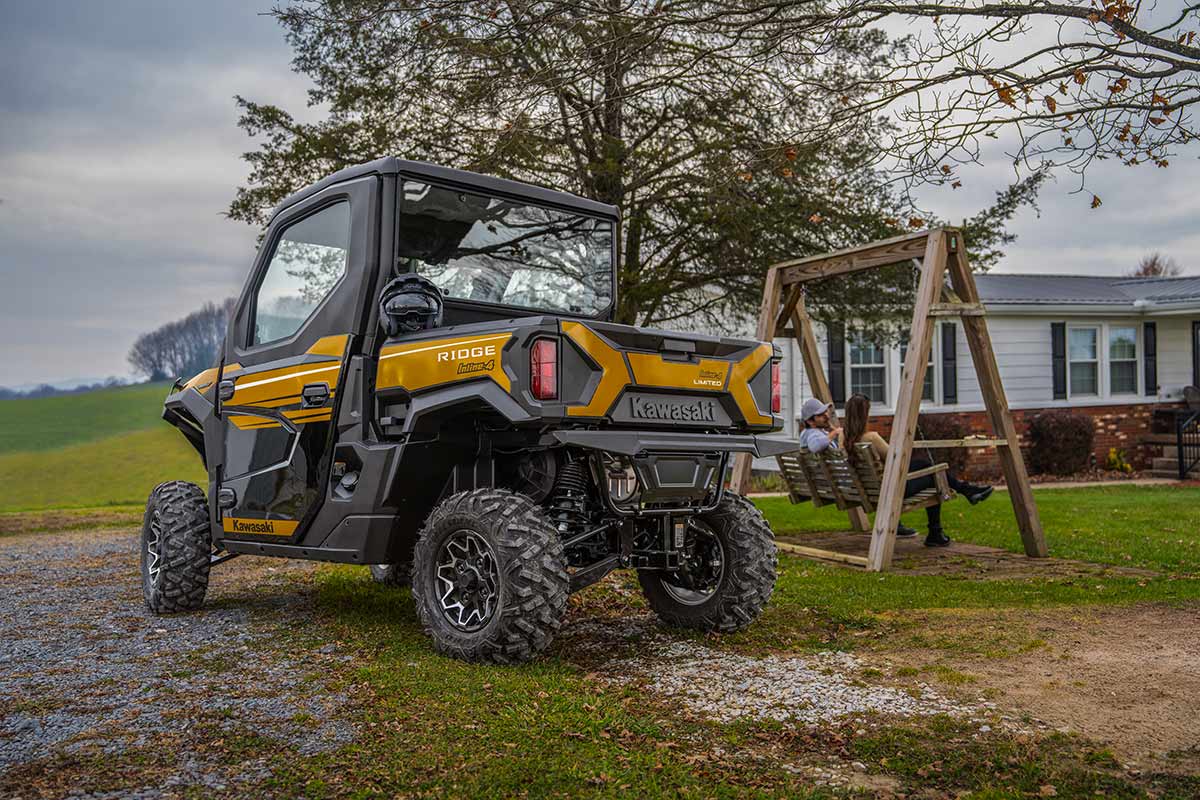 Three-quarter rear angle of a side x side parked next to a swing set.