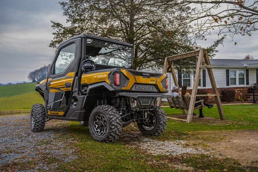 Three-quarter rear angle of a side x side parked next to a swing set. opens in a new window