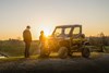 Three-quarter front angle of a side x side parked in front of a sunset.
