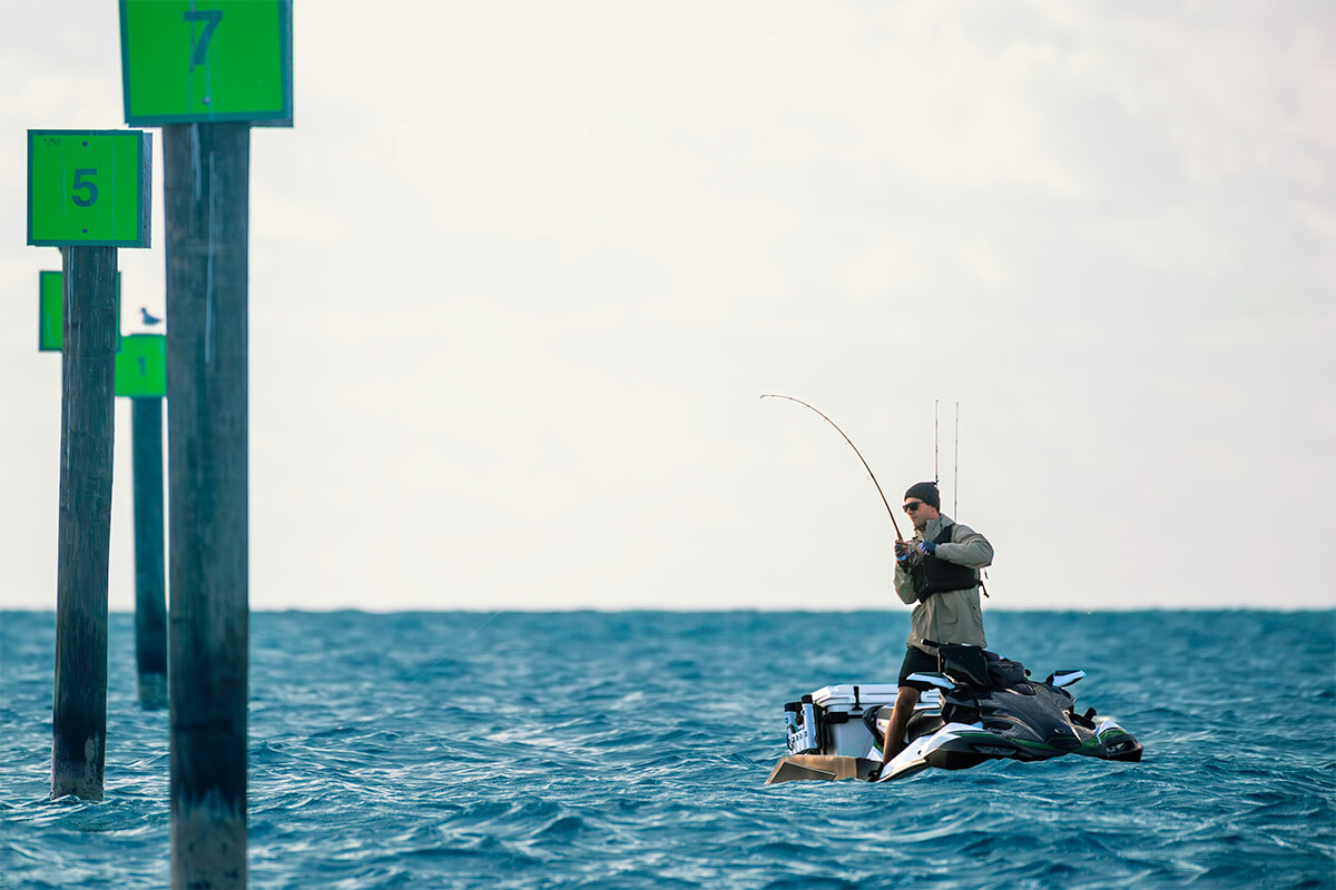 Three-quarter front angle of a person standing on a personal watercraft in water.