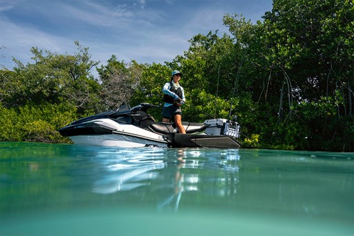Side angle of a person standing on a personal watercraft. opens in a new window