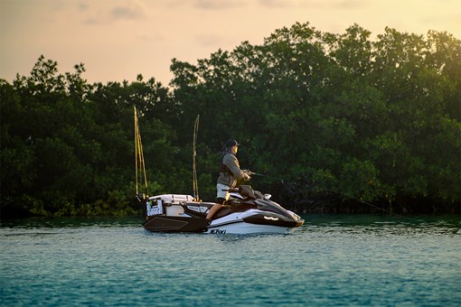 Side angle of a person fishing on a personal watercraft in the water. opens in a new window