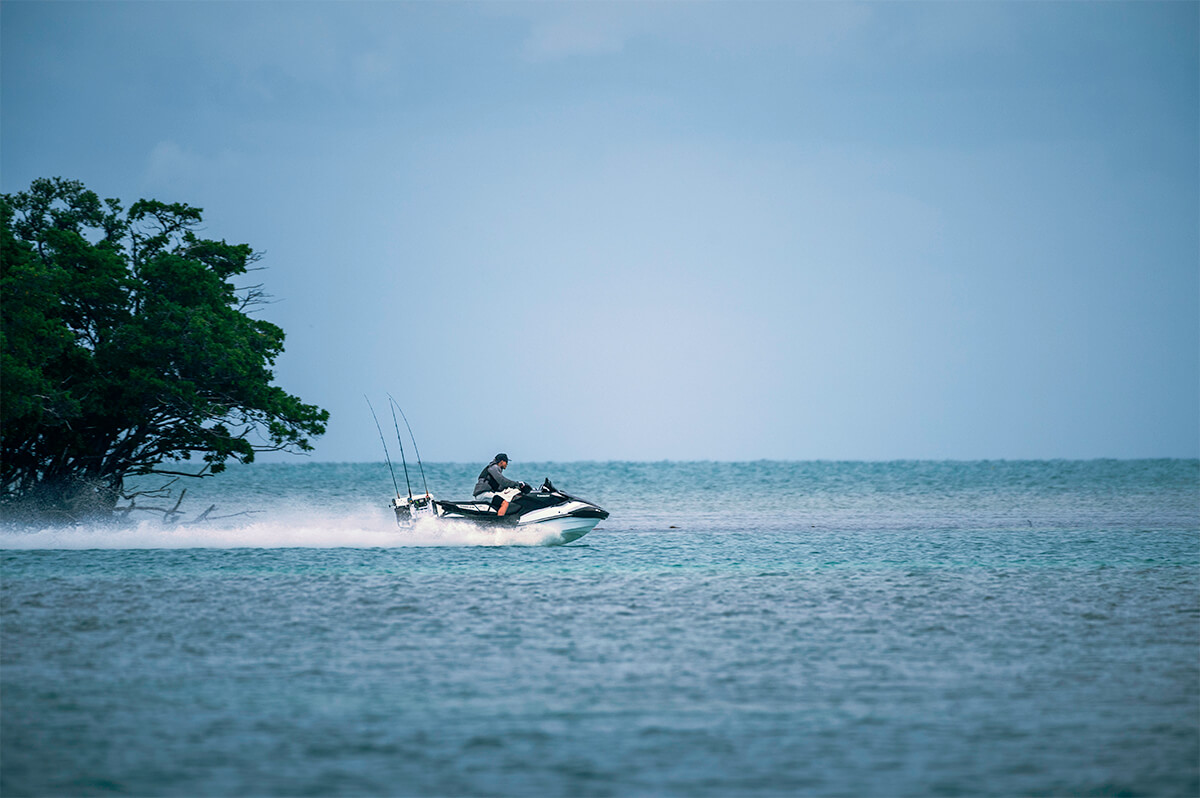 Profile angle of a person riding a personal watercraft into open water.