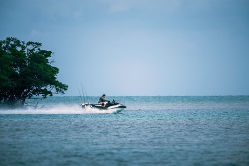 Profile angle of a person riding a personal watercraft into open water. opens in a new window
