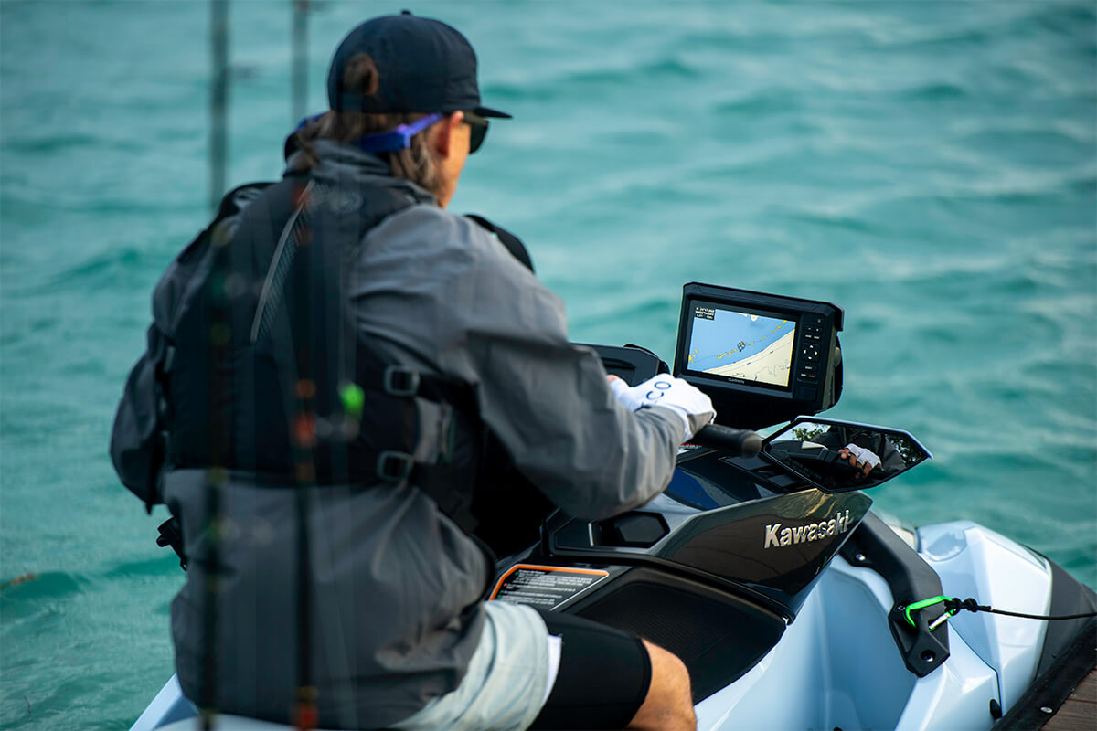 Three-quarter rear angle of a person seated on a personal watercraft in water.