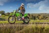 Side angle of a person sitting on a parked motorcycle off-road.