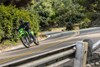 Three-quarter front angle of a person coming out of a turn while riding a motorcycle on a highway.