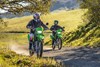Three-quarter front angle of two people riding motorcycles off-road.