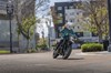 Three-quarter front angle of a person coming out of a turn on a motorcycle in an urban city.