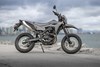 Side angle of a motorcycle staged on a road near a body of water.