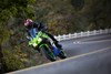 Front angle of a person riding a motorcycle on a curving road.