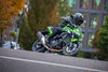 Three-quarter front angle of a person riding a motorcycle on a street.