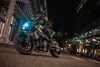 Three-quarter front angle of a person riding a motorcycle on a city street.