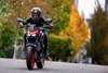 Front angle of a person riding a red motorcycle on a road.