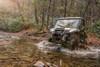 Front angle of a person driving a side x side through water.