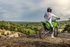 Three-quarter rear angle of a person stationary on a motorcycle overlooking a scenic vista.