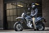 Side angle of a person sitting on a parked motorcycle.