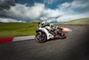 Three-quarter front angle of a person riding a motorcycle on a racetrack.