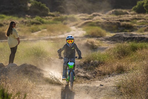 Front angle of a young adult riding an electric balance bike from a distance.  opens in a new window