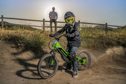 Side angle of a young adult sitting on an electric balance bike parked.  opens in a new window