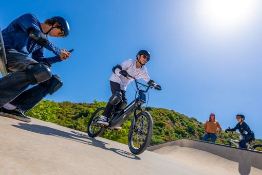 Ground level angle of a young adult riding an electric balance bike. opens in a new window