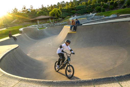 Overhead angle of a young adult riding an electric balance bike around a large turn. opens in a new window