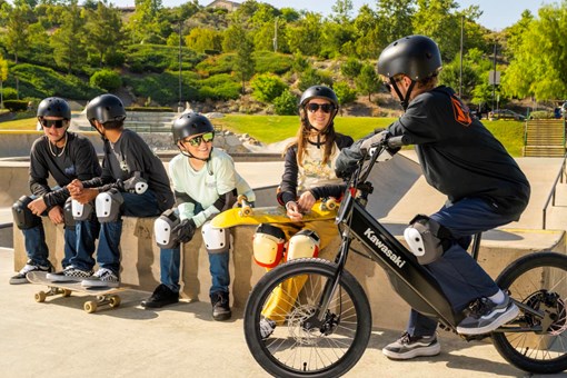 Side angle of a young adult riding an electric balance bike with friends nearby. opens in a new window