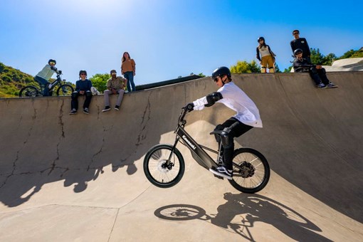 Upward side angle of a young adult riding an electric balance bike. opens in a new window