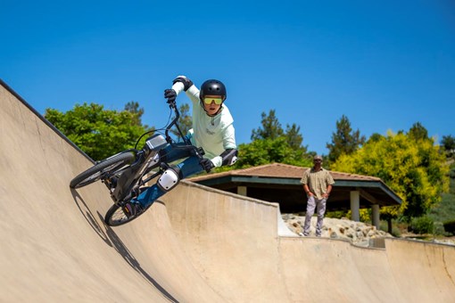 Front angle of a young adult riding an electric balance bike up the outer edge of the skate park. opens in a new window