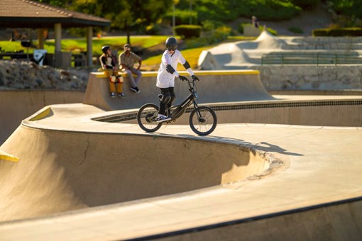 Side angle of a young adult riding an electric balance bike in a skate park. opens in a new window