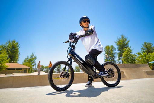 Three-quarter front angle of a young adult sitting on an electric balance bike. opens in a new window