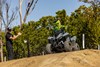 Three-quarter front angle of a person riding a gray ATV off-road.