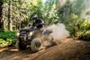 Three-quarter front angle of a person riding an ATV on a dirt trail.