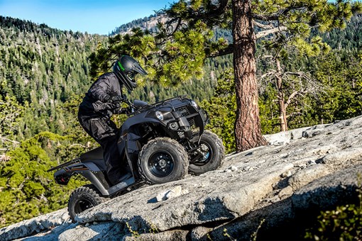 Three-quarter front angle of a person riding an ATV up a rocky mountain. opens in a new window