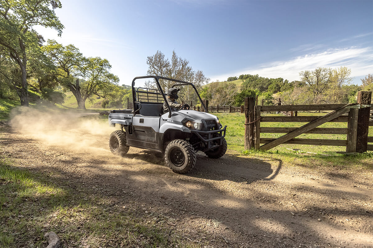 Three-quarter front angle of a person driving a side x side on a dirt trail.