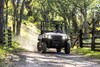 Three-quarter front angle of a person driving a side x side off-road.