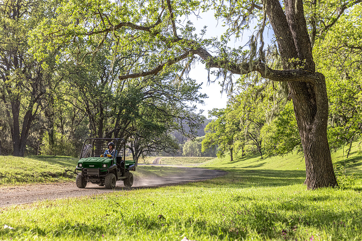 Three-quarter front angle of a person driving a side x side on a dirt trail.