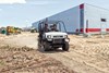 Three-quarter front angle of a person driving a side x side on a job site.