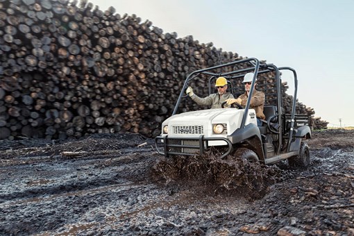 Three-quarter front angle of a person driving a side x side through muddy terrain. opens in a new window