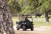 Three-quarter front angle of a person driving a side x side on a dirt road.
